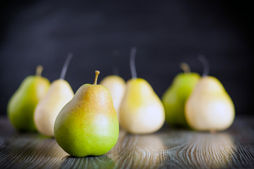Green pears on wooden table dark background front view
