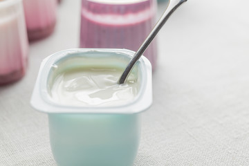 Yogurts assortment  in plastic bowls on light cloth background. Natural and fruit healthy, diet, gourmet dessert for granola breakfast. Sweet yoghurts closeup.
