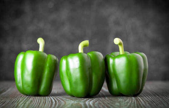 Green bell pepper on wooden board dark background front view