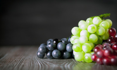 Colorful grape on wooden board dark background copy space