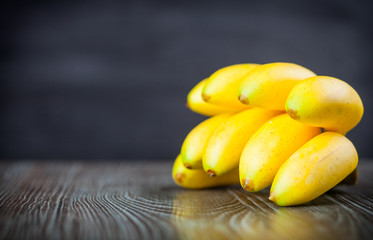 Bunch of bananas on wooden table dark background copy space