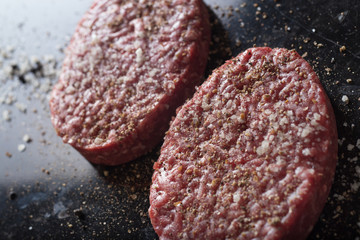 Meat for burgers, grilling, barbecue, bbq. Fresh, spicy, uncooked, delicious beef for hamburgers on dark background with copy space closeup
