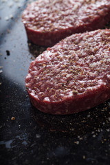 Meat for burgers, grilling, barbecue, bbq. Fresh, spicy, uncooked, delicious beef for hamburgers on dark background with copy space closeup
