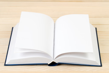 Open hardback book on wooden table. Back to school. Copy space
