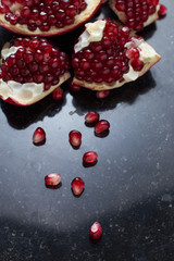Red juicy pomegranate on dark marble background. Healthy, antioxidant, fresh, gourmet, delicious, organic fruit. Ingredient for grenadine. Close-up and copy space.