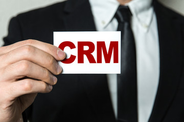 Business man holding a card with the text: CRM