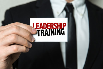 Business man holding a card with the text: Leadership Training