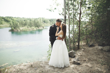 Fototapeta na wymiar Wedding couple in love kissing and hugging near rocks on beautiful landscape