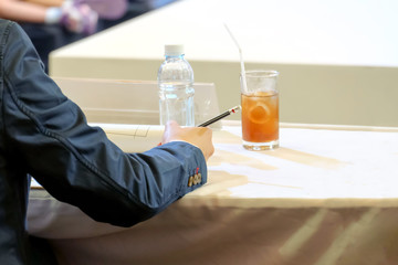 The arms of a referee or commentator wearing a suit and holding a pencil on paper.