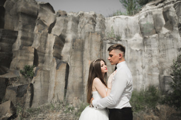 Obraz na płótnie Canvas Wedding couple in love kissing and hugging near rocks on beautiful landscape