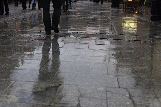 Walking along wet pavement street. Rain in the city. 