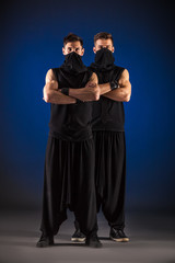 Two male dancers posing in ninja costumes against blue backgroun © Dmytro Panchenko