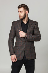 Studio portrait of handsome elegant young man in brown jacket po