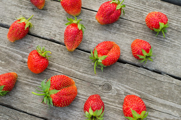 Summer berries topic: Ripe red strawberries bunch of lies on gray wooden table in the garden, view from above