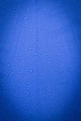 Obraz na płótnie Canvas Rain water drop on blue background, vertical style