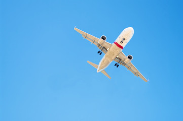 view of airplane flying above in clear blue sky
