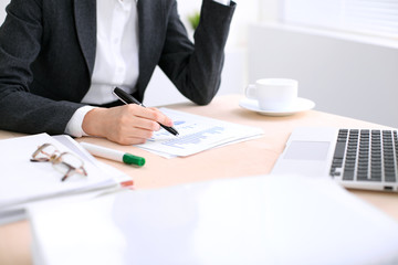 Business woman  is sitting at the table and working in  white colored office.