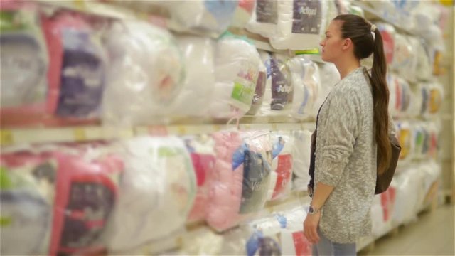 Young woman chose a pillow in a supermarket, biautiful wife buyes blanket for a new house