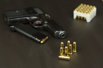 Handgun with ammunition on a dark wooden table. Sales of weapons and ammunition. Advertising on ammunition. New gun and ammunition. Grocery ammunition. The supply of ammunition for the defense.
