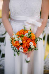 Orange bouquet in hands of bride