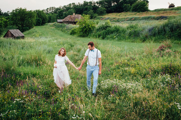 Naklejka na ściany i meble Happy Bride and groom walking on the green grass