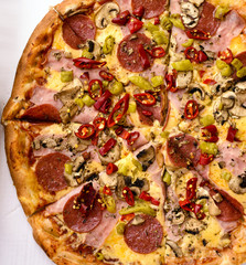 Italian pepperoni pizza with ham, red peppers and cheese