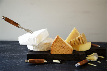 Different types of cheese with accessories for cheese on a dark background 
