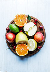 Fresh fruits over dark board on light blue background.