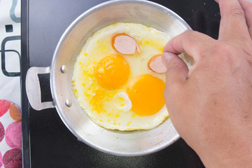 Chef putting slice of sausage to the pan