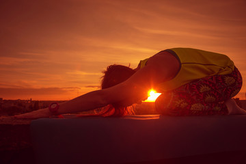 Fototapeta na wymiar Young girl yoga on the roof. Silhouette
