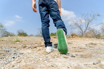 Boy walking on the rocky land.