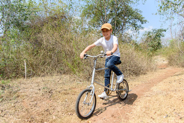 Naklejka premium Little boy ride bicycle on the rock road.
