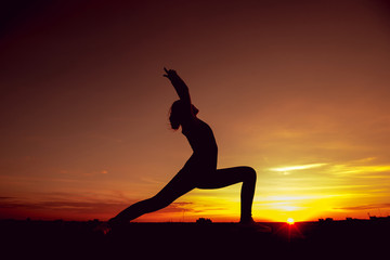 Young girl yoga on the roof. Silhouette