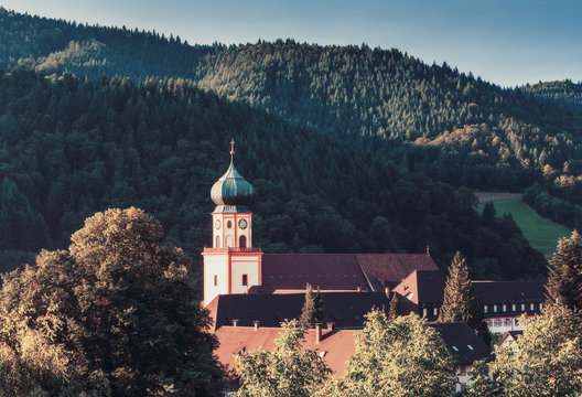Scenic countryside landscape: summer mountain valley with forests, fields and old monastery in Germany, Black Forest.