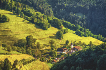 Scenic countryside landscape: summer mountain valley with forests, fields and old church in Germany, Black Forest
