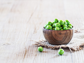 Fresh, young green peas in a wooden bowl, selective focus.