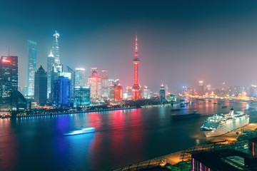 Obraz premium Big modern illuminated city by night. Shanghai, China. Nighttime skyline with skyscrapers and the Hunapu river.