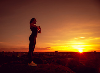 Fototapeta premium Young girl yoga on the roof. Silhouette