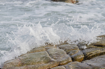 Wave crashing on rock beach