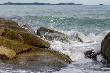 Wave crashing on rock beach