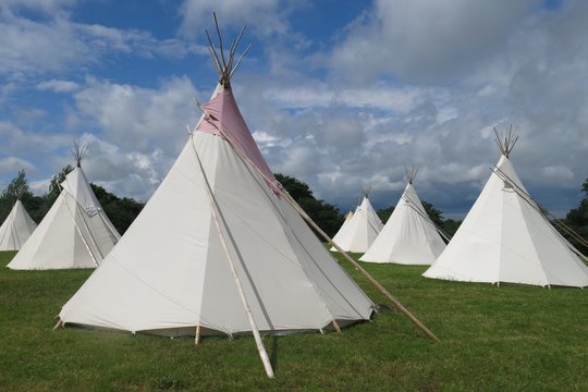 Glamping camping tipis tepees in a field on sunny day