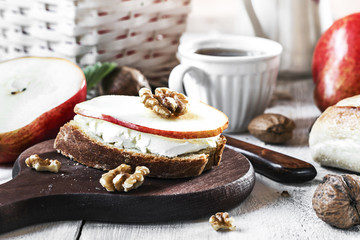 Sandwich with cream cheese, pears and nuts for breakfast on a dark board, selective fosus.