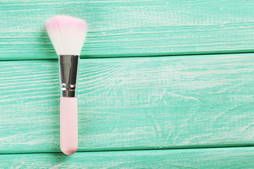 Makeup brush on a mint wooden background
