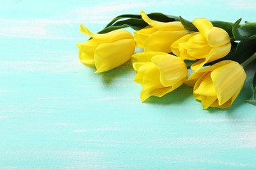 Bouquet of yellow tulips on a mint wooden table
