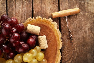 Wine corks and tailspin with bunch of grapes on wooden background