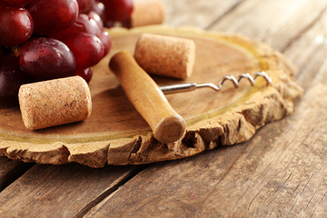 Wine corks and tailspin with bunch of grapes on wooden background