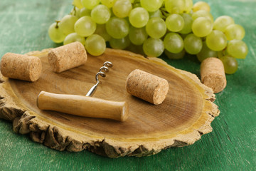 Wine corks and tailspin with bunch of grapes on wooden background