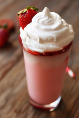 Delicious strawberry milkshake on wooden table