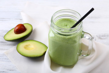 Delicious fresh avocado smoothie on white wooden background