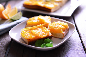 Plate with delicious citrus cake on wooden background